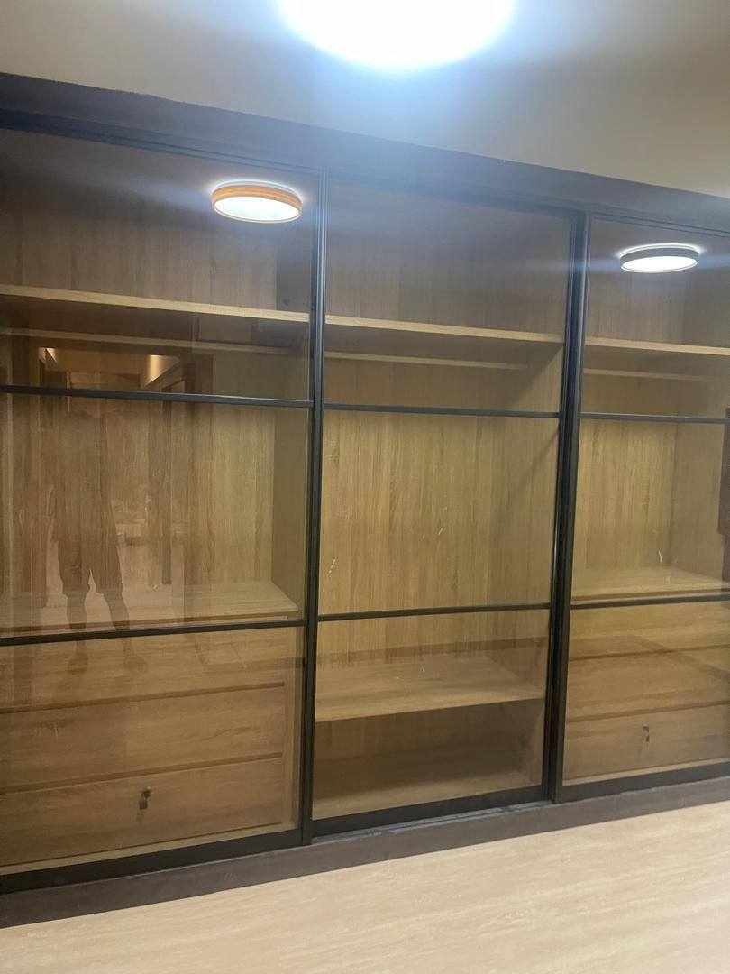 Black-framed glass-door aluminium cabinet with timber-tone interior shelves
