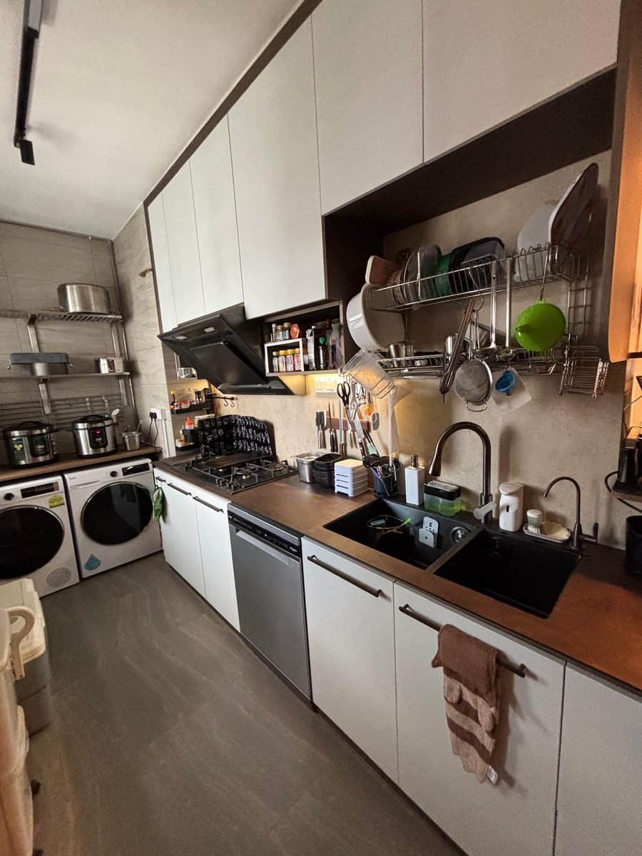 Lived-in kitchen with white aluminium cabinets, wood-tone countertop and washer dryer