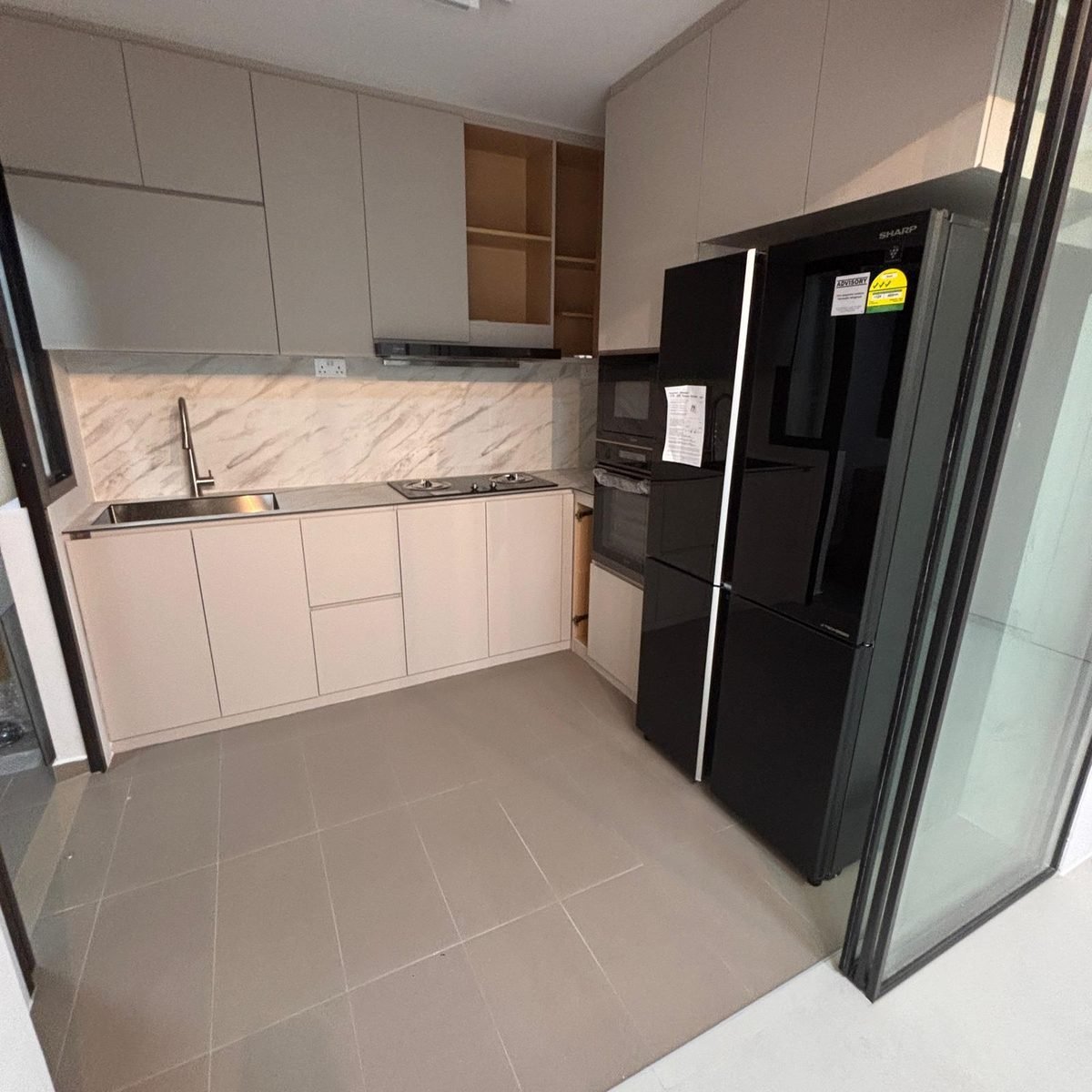 White aluminium kitchen cabinets with marble-pattern backsplash and black fridge